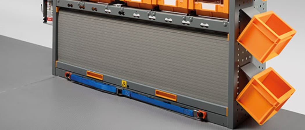 Module de rangement à rideau roulant fermé, avec bacs à bec orange fixés sur le montant latéral