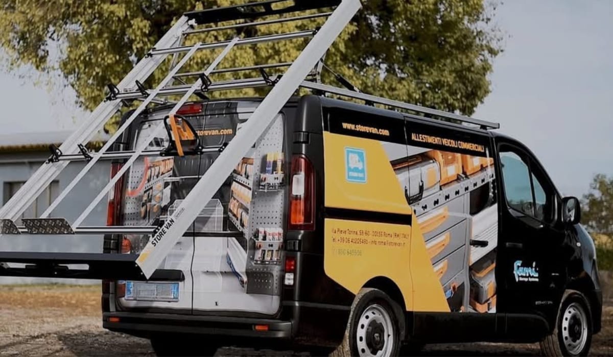 Renault Trafic lettré avec galerie de toit, échelle et rampe de chargement, rayonnage visible par les portes arrière ouvertes