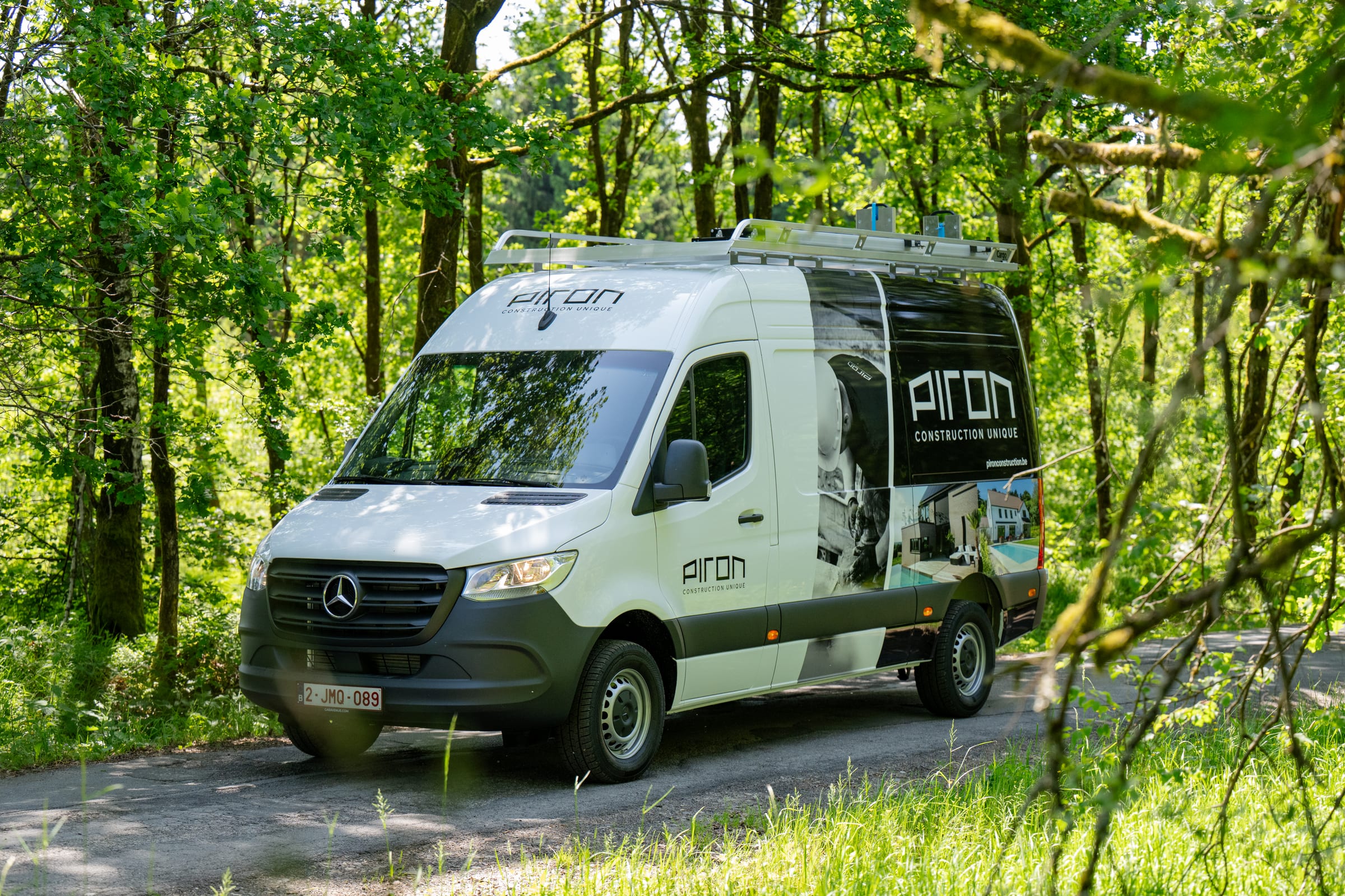 Mercedes Sprinter aménagé et lettré Piron Construction, galerie de toit et échelle, sur un chemin forestier
